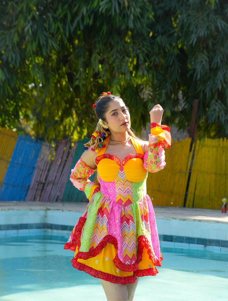 Model in bright multicolor Famameha boho mini dress with sweetheart bodice, bell sleeves, and ruffled hem, poolside front view.