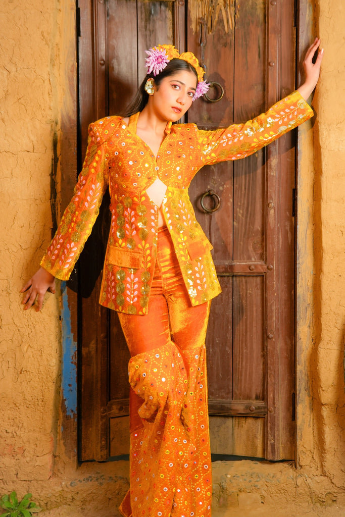 Full-length view of the Ruhani Mustard Velvet Blazer Co-ord Set with mirror embroidery, front cutout blazer and flared pants styled at a rustic doorway.